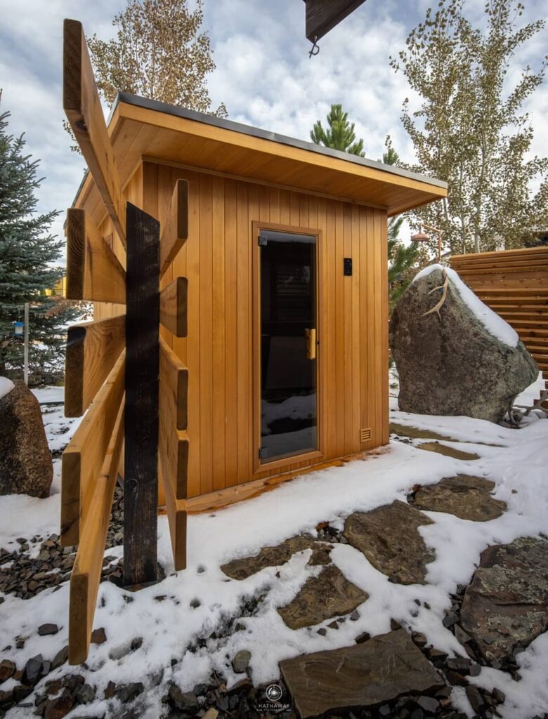 outdoor finnleo sauna surrounded by trees and a fence.